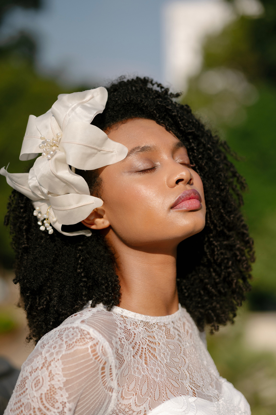 Noiva com os olhos fechados, sob luz natural, com flores no cabelo